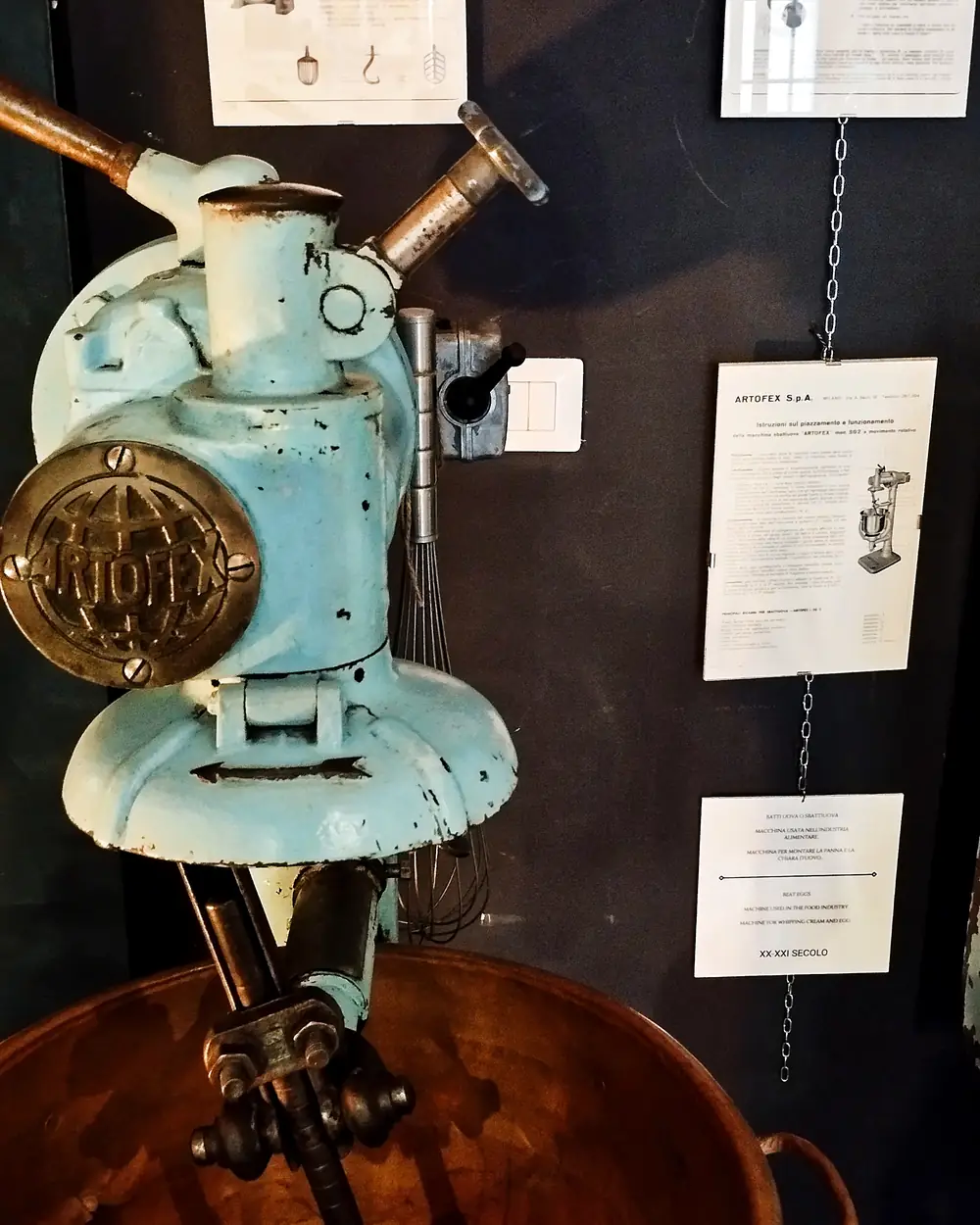 Restored Artofex mixer at Artefact, with the original machine documentation displayed on the wall behind it